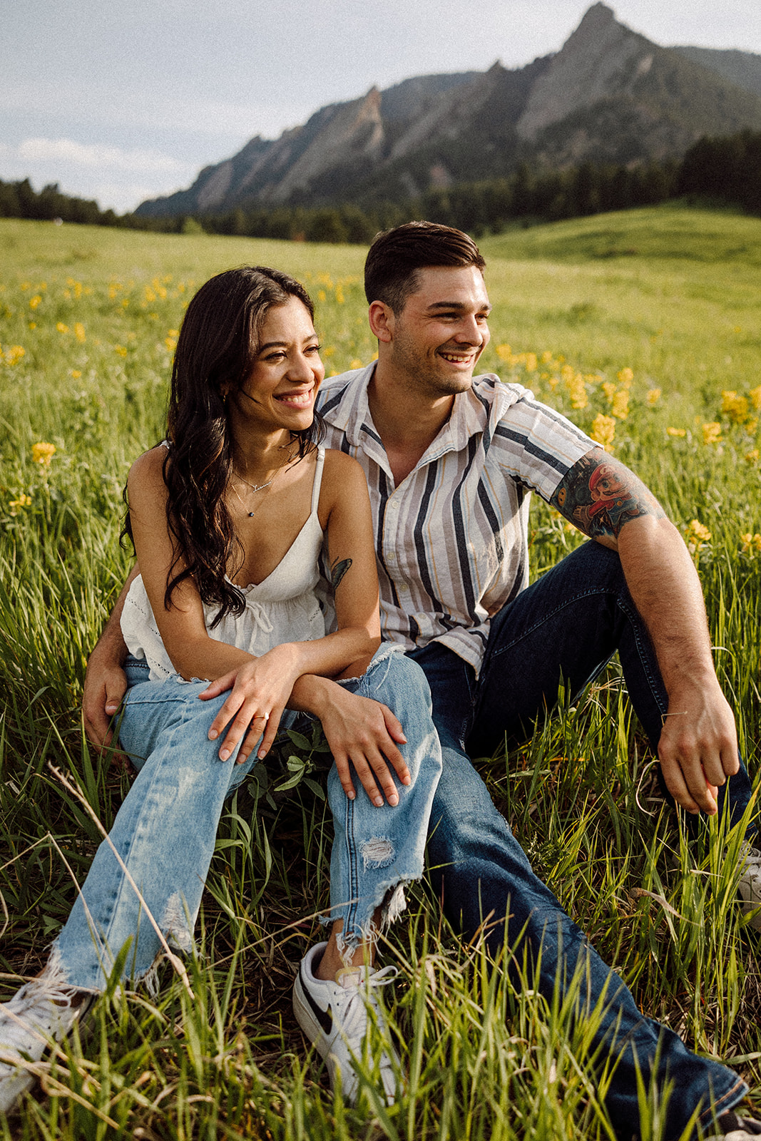 A man and a woman sitting in a meadow with mountains in the background 