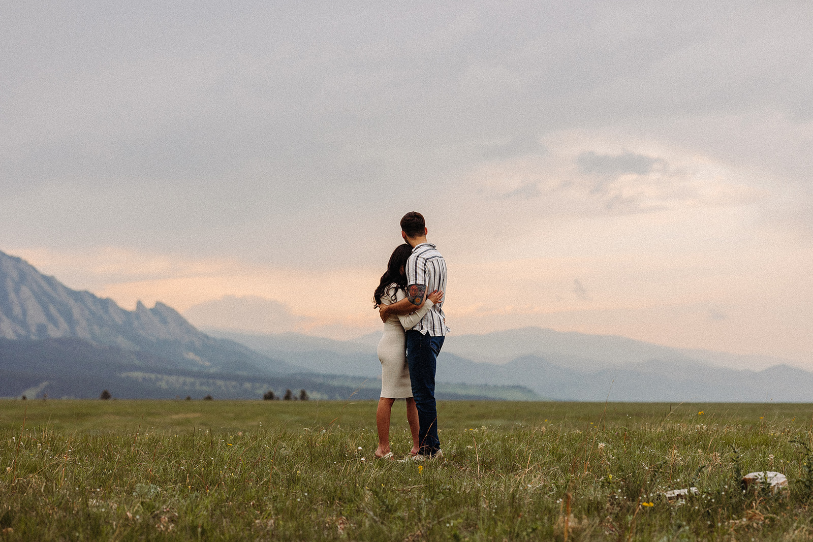A man and woman hugging while looking at a mountian view