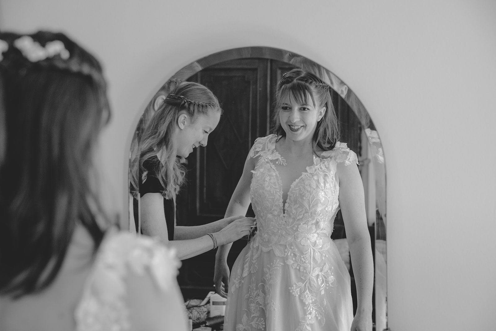 Bride getting dressed with help from her sister with the dress