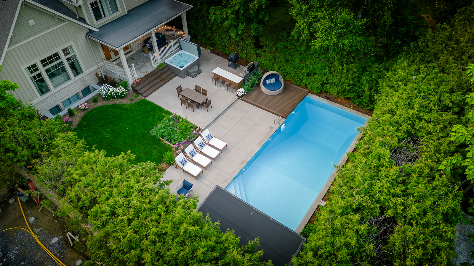 A done shot of an inground pool, and seating areas in the back yard.