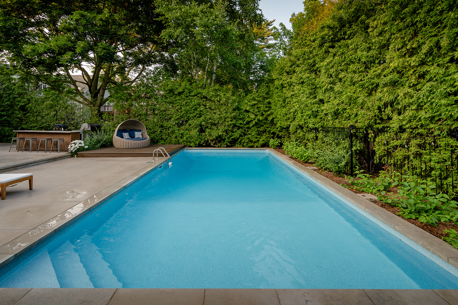An inground pool with a seating area in the corner.