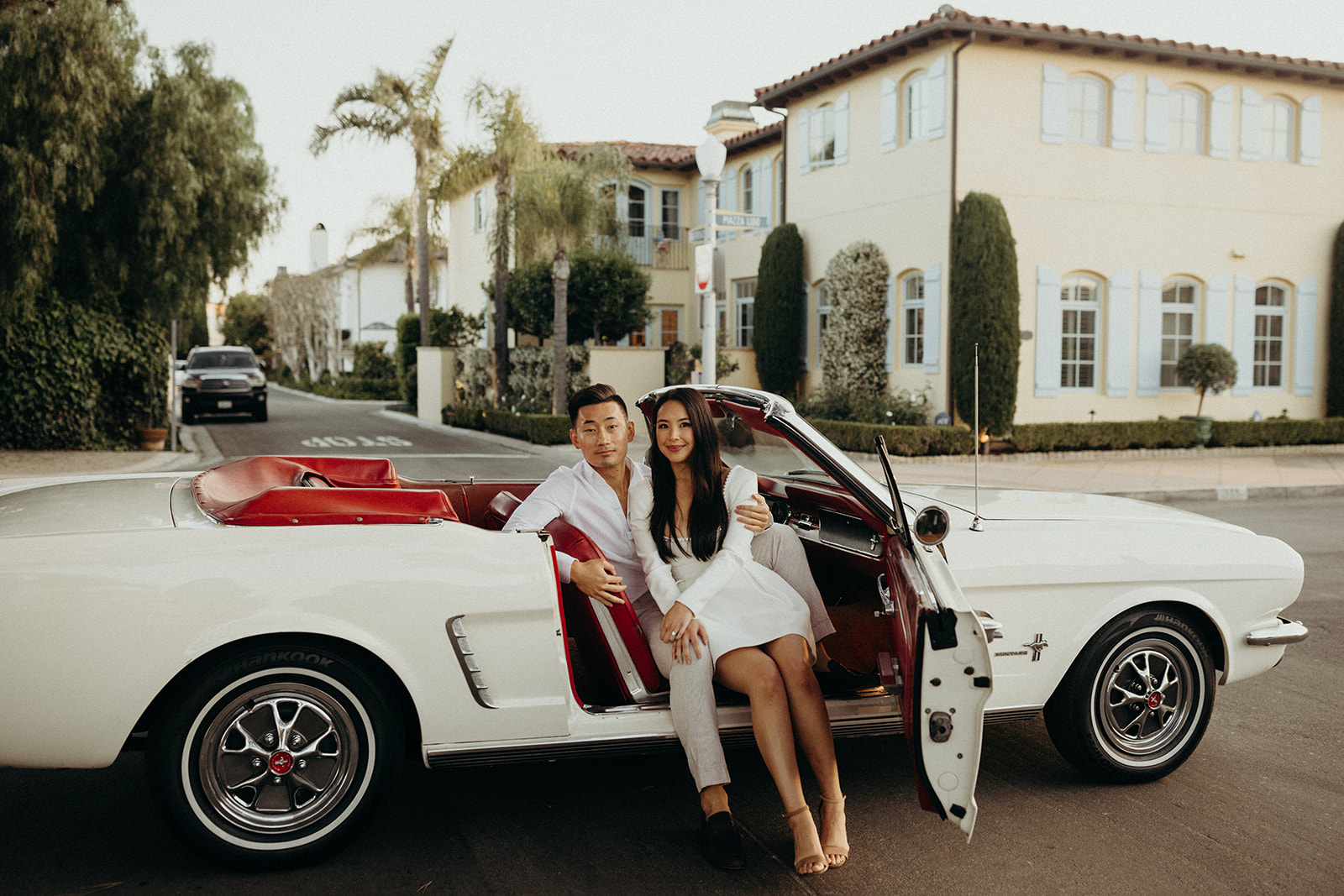 couple sitting a white vintage mustang for engagement session