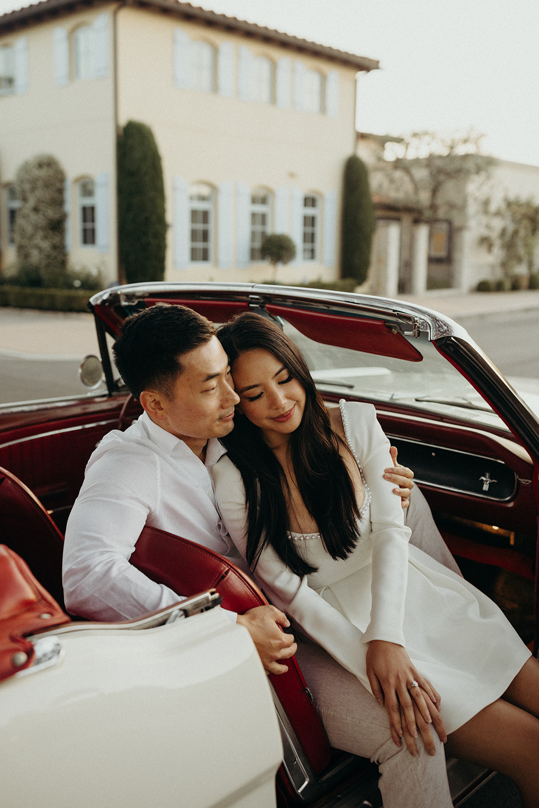 couple snuggling together in the passenger seat of a white vintage mustang car