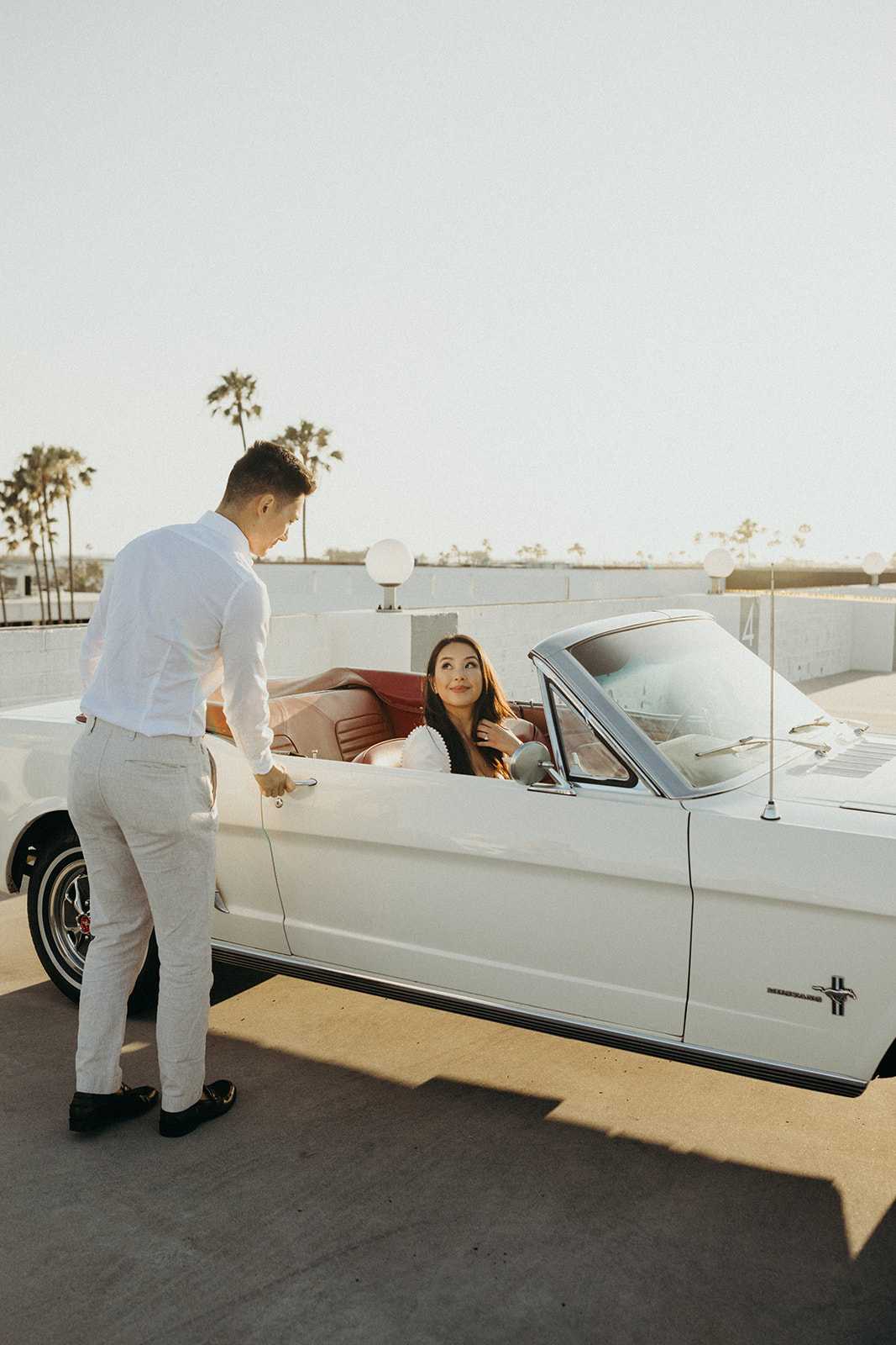 girl getting into a white vintage mustang