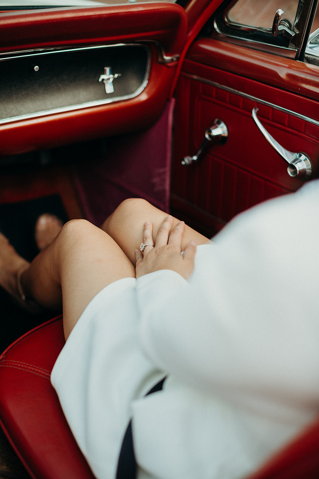 red leather interior of white mustang with a woman sitting in passenger seat wearing white