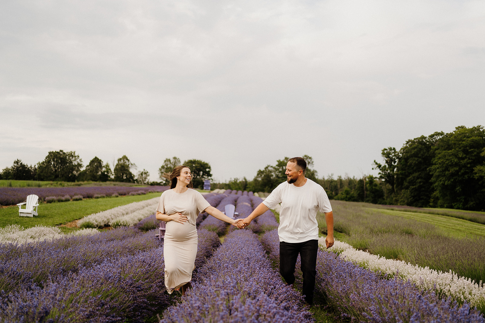 Man and woman walk in separate isles of lavender while holding hands.