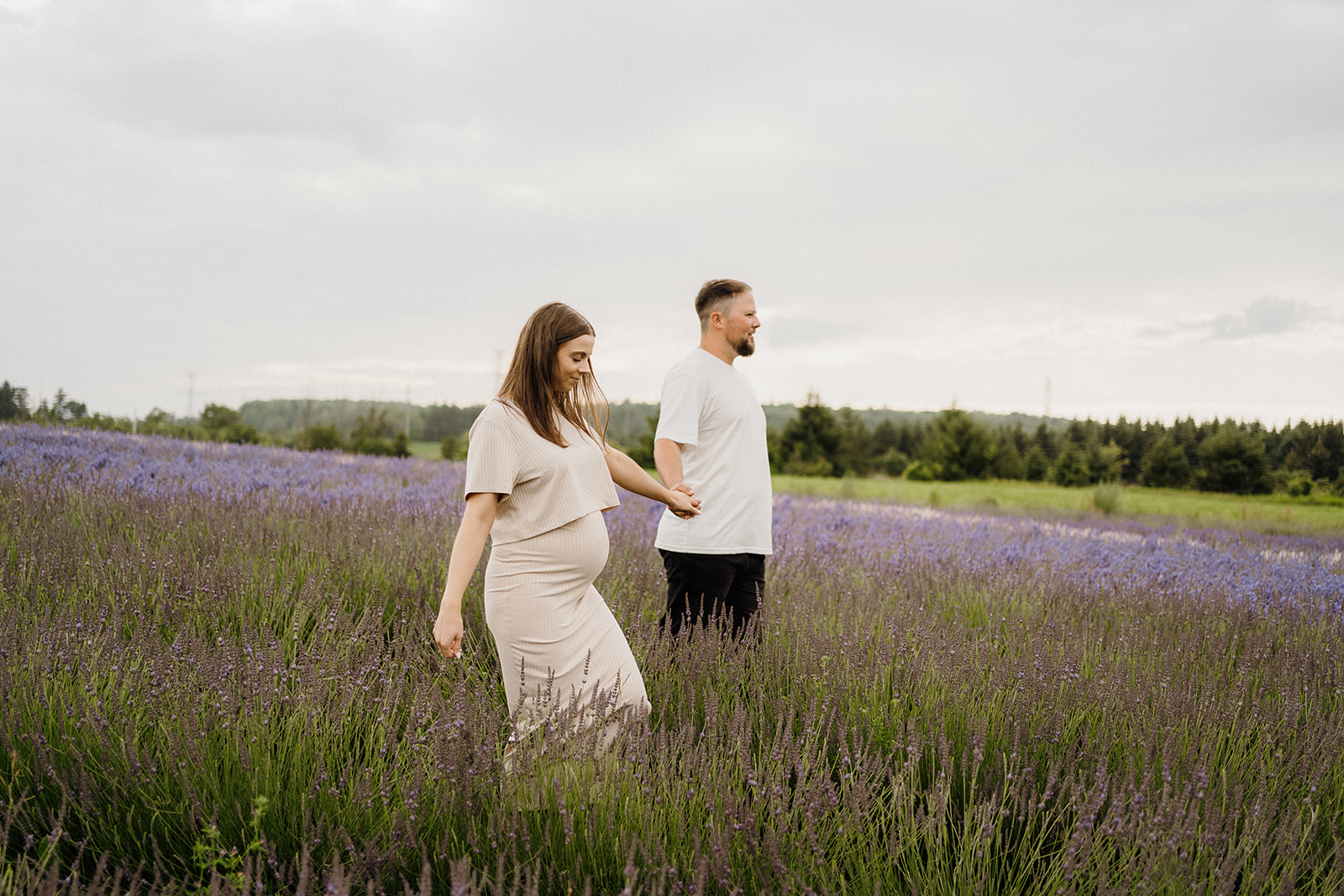 Two people holding hands in a lavender field.