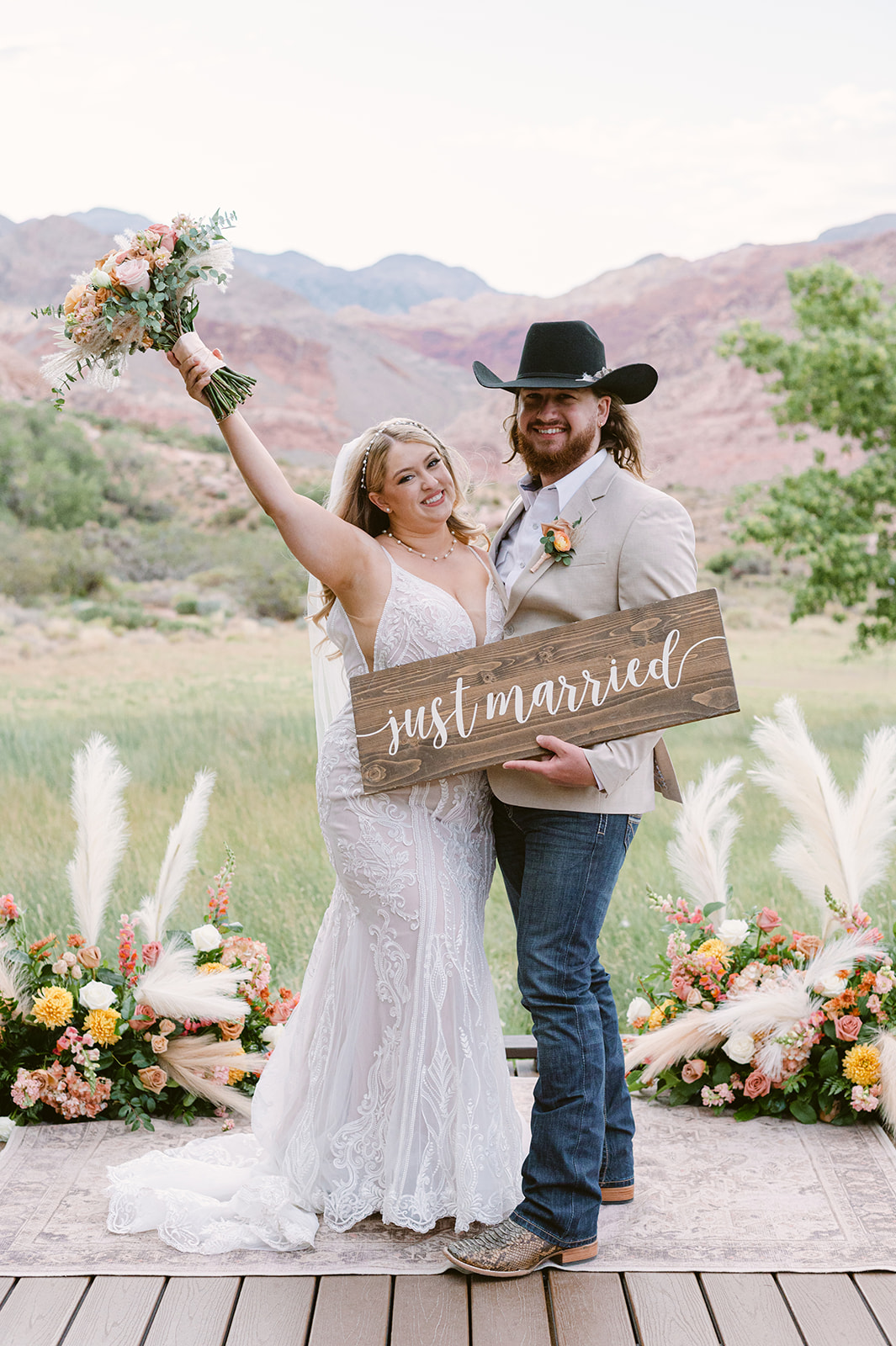 A couple who eloped in Red Rock Canyon Nevada celebrate in front of the red rock mountain backdrop and floral backdrop