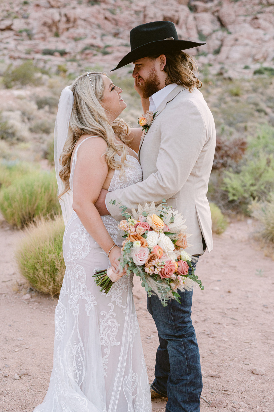 A couple who eloped in Red Rock Canyon Nevada embrace in front of the red rock mountain backdrop
