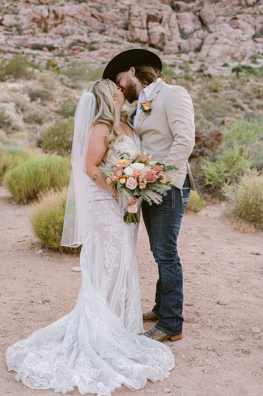 A couple who eloped in Red Rock Canyon Nevada share a kiss in front of the red rock mountain backdrop