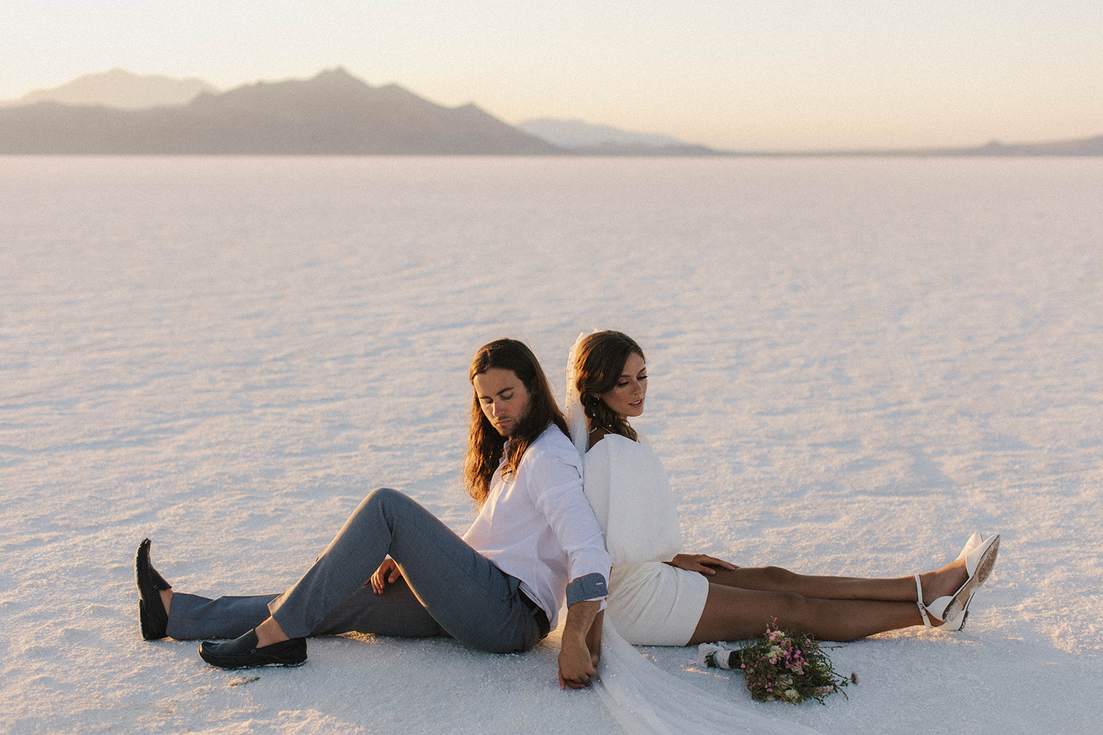 couple sits on salt flats during sunset elopement