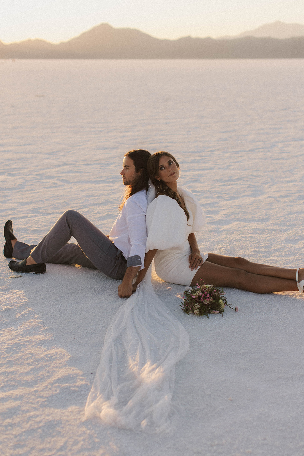 couple sits side by at salt flats elopement