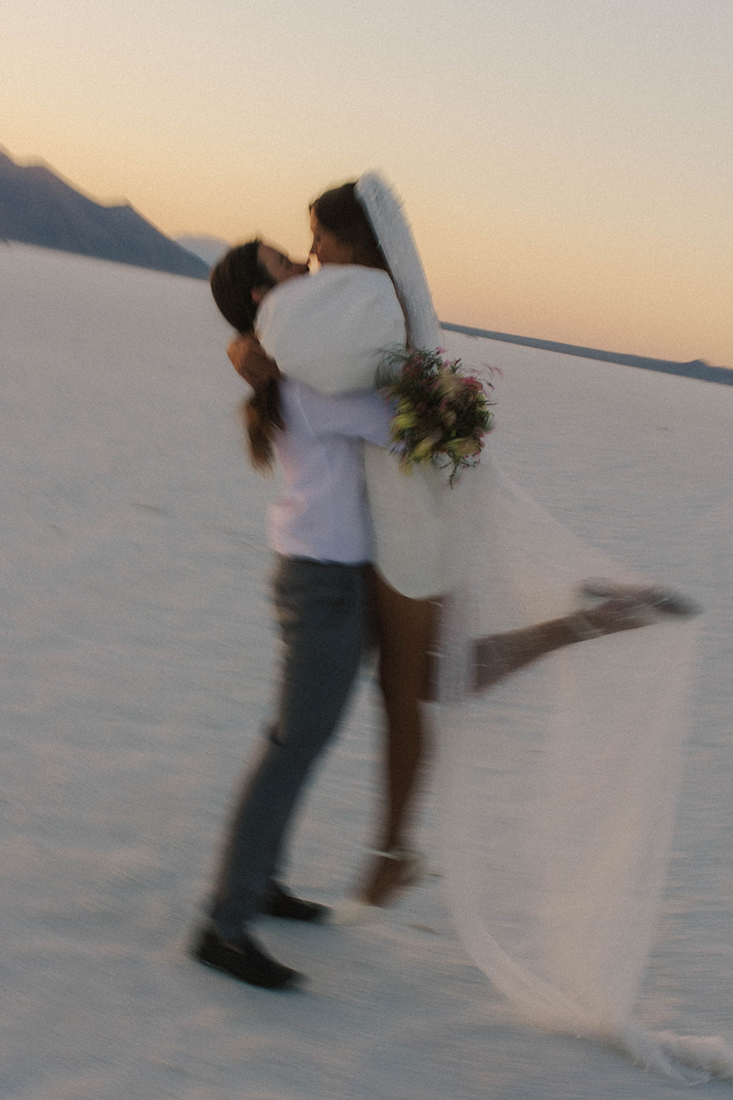 groom carries bride at salt flats elopement