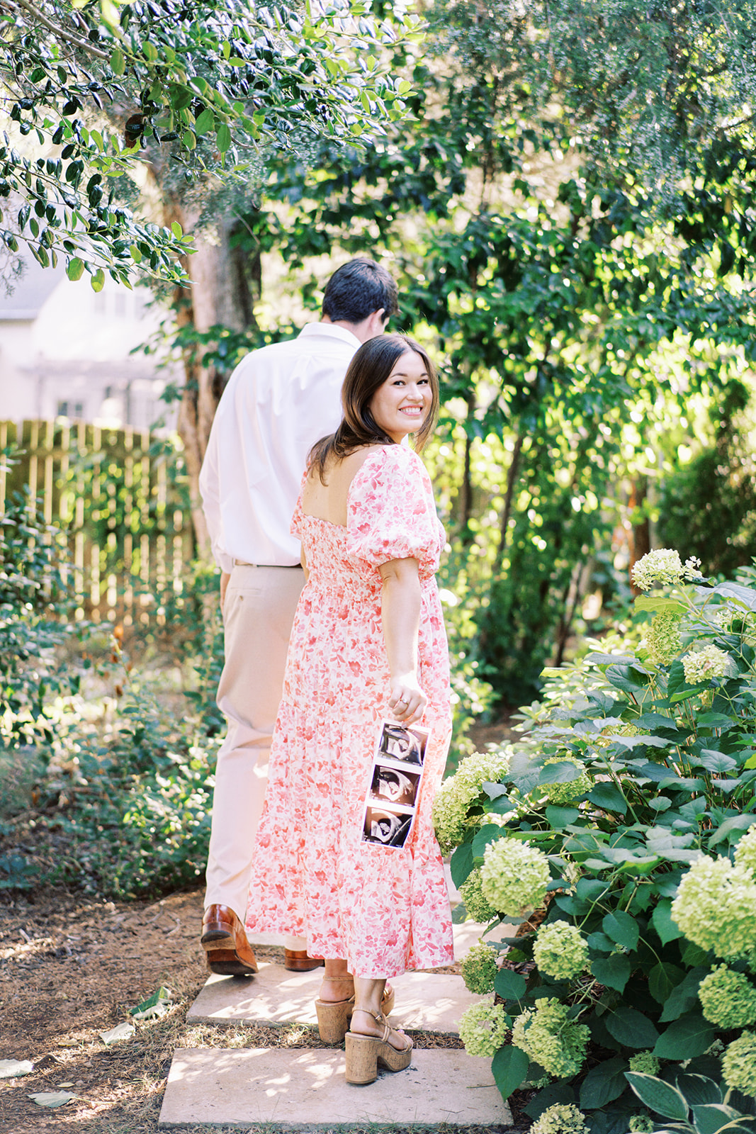 A couple walk through a vibrant summer garden with surprising news by Huntsville photographer Kelsey Dawn