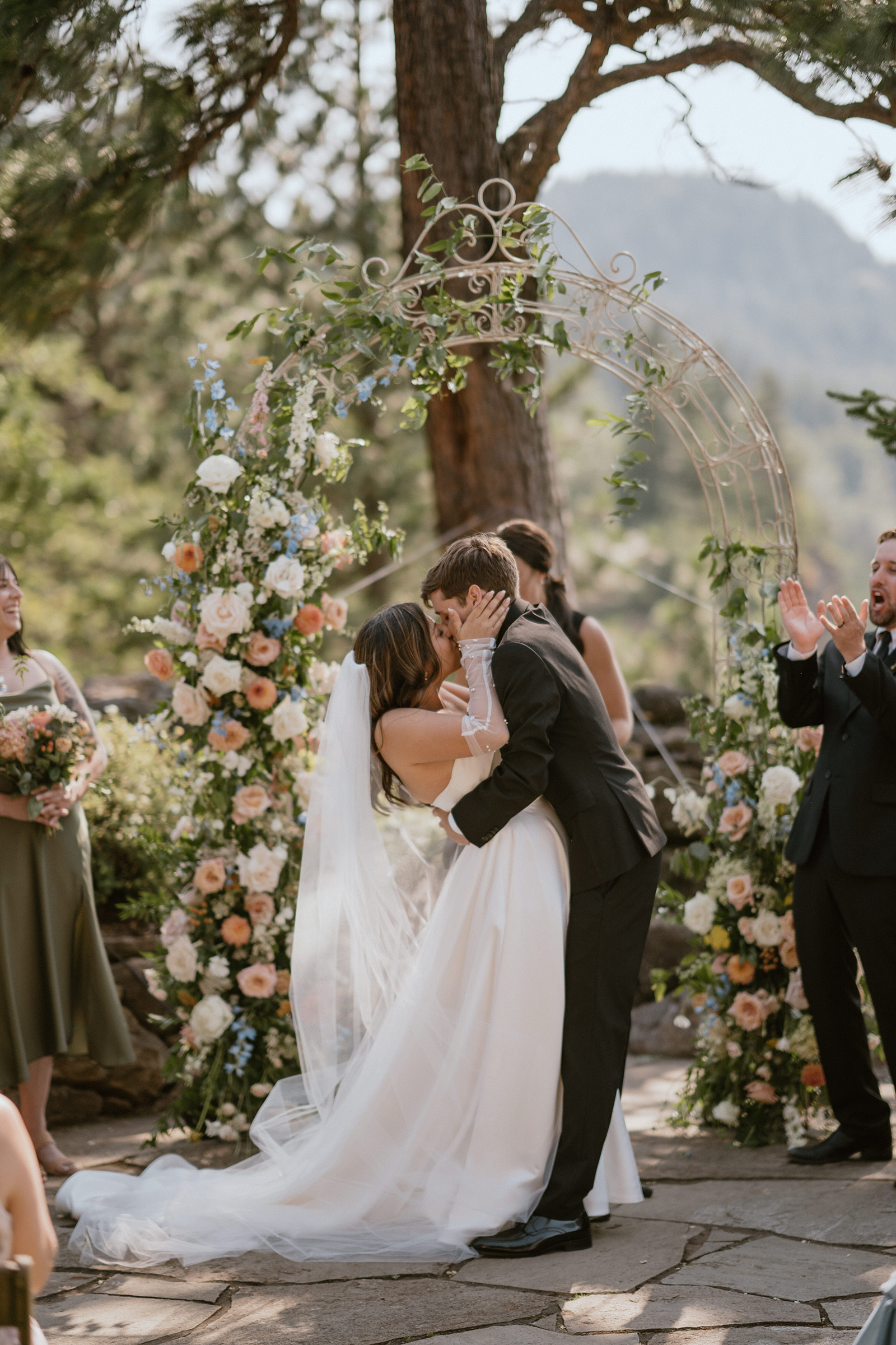 Bride and groom share their first kiss in front of a flower arch at the Griffin House on the Columbia River Gorge