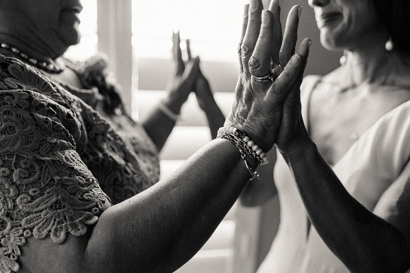 A black and white photo of the bride and her mom touching palms, a special moment between the two.