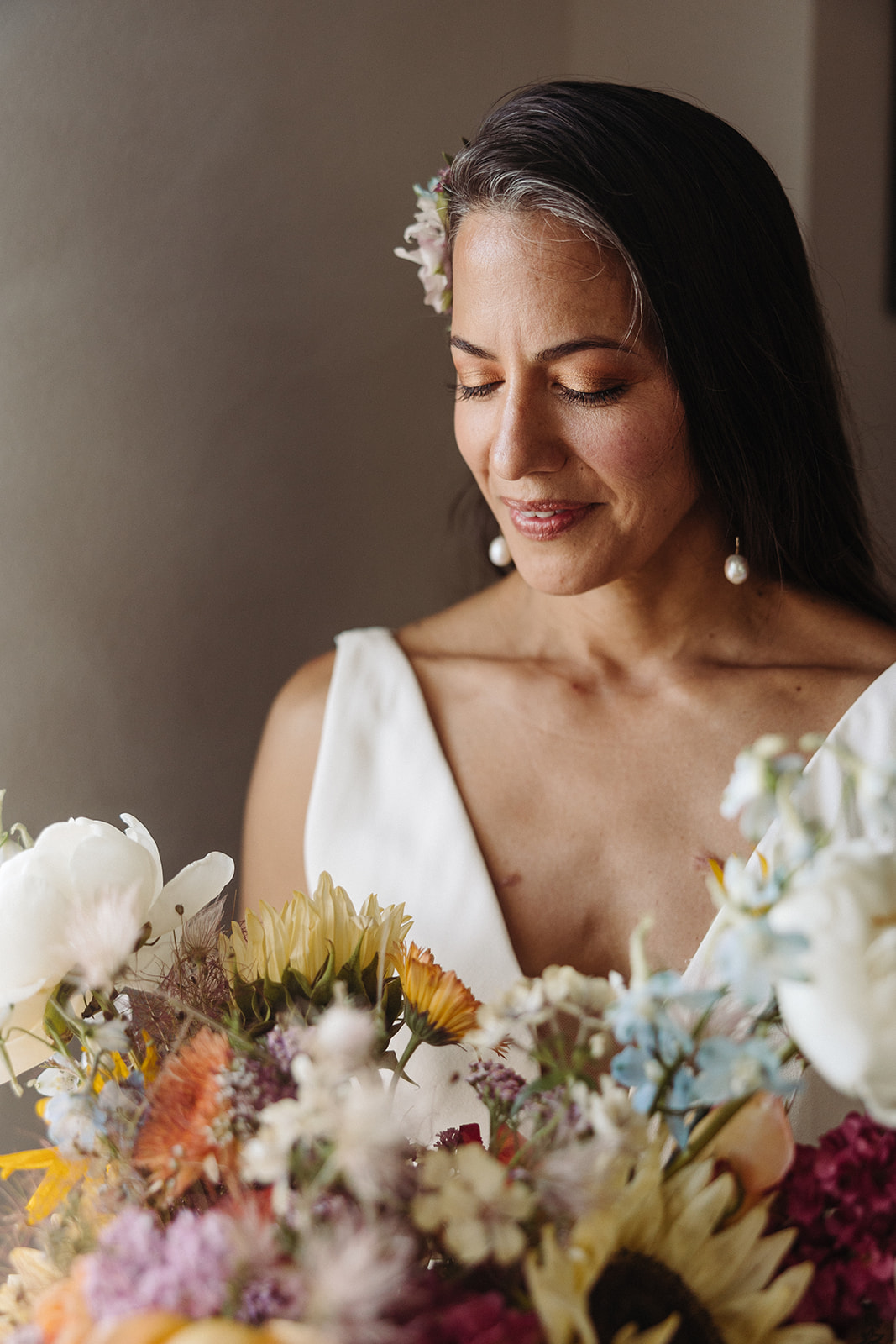 A portrait of the bride looking down at her colorful bouquet, admiring the natural beauty.