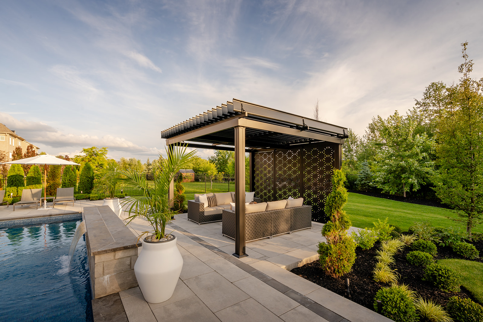 A metal gazebo with an outdoor patio set underneath, beside an inground pool.