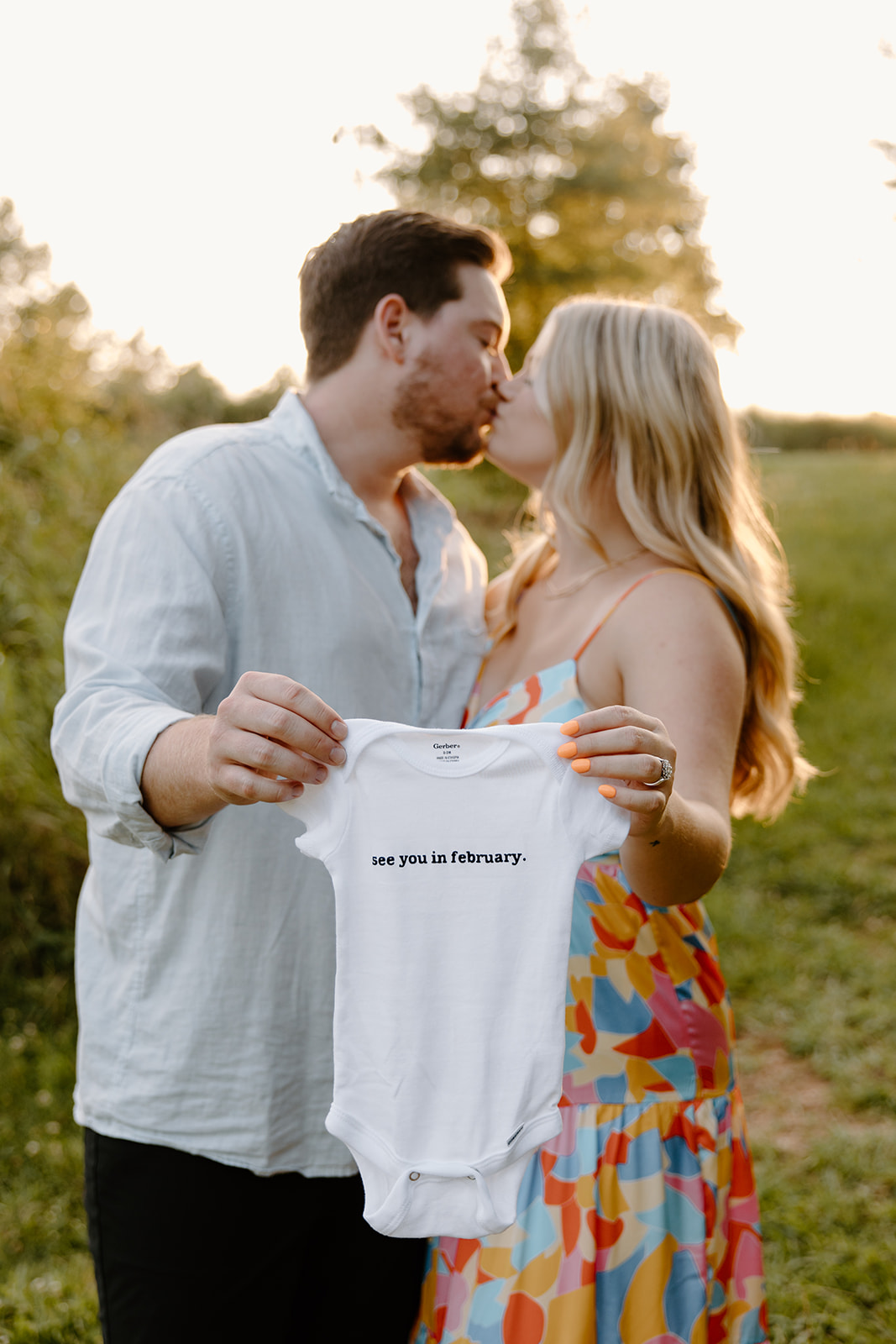 Pregnancy announcement pictures at a field.