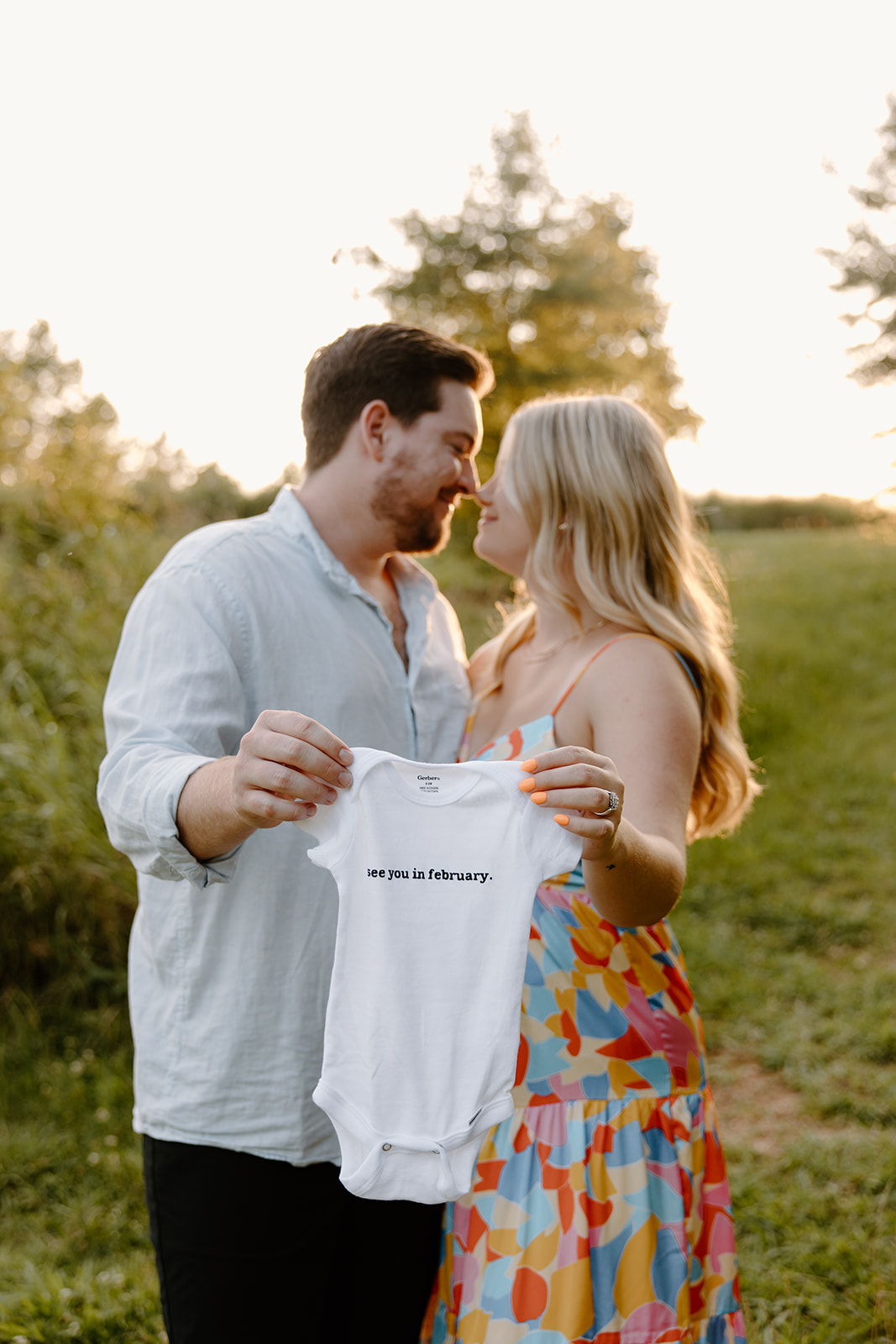 Pregnancy announcement pictures at a field.