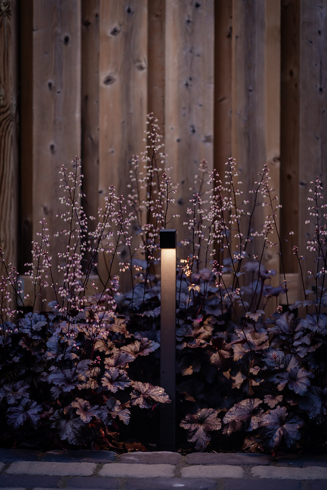 A lit lamp post in the garden.