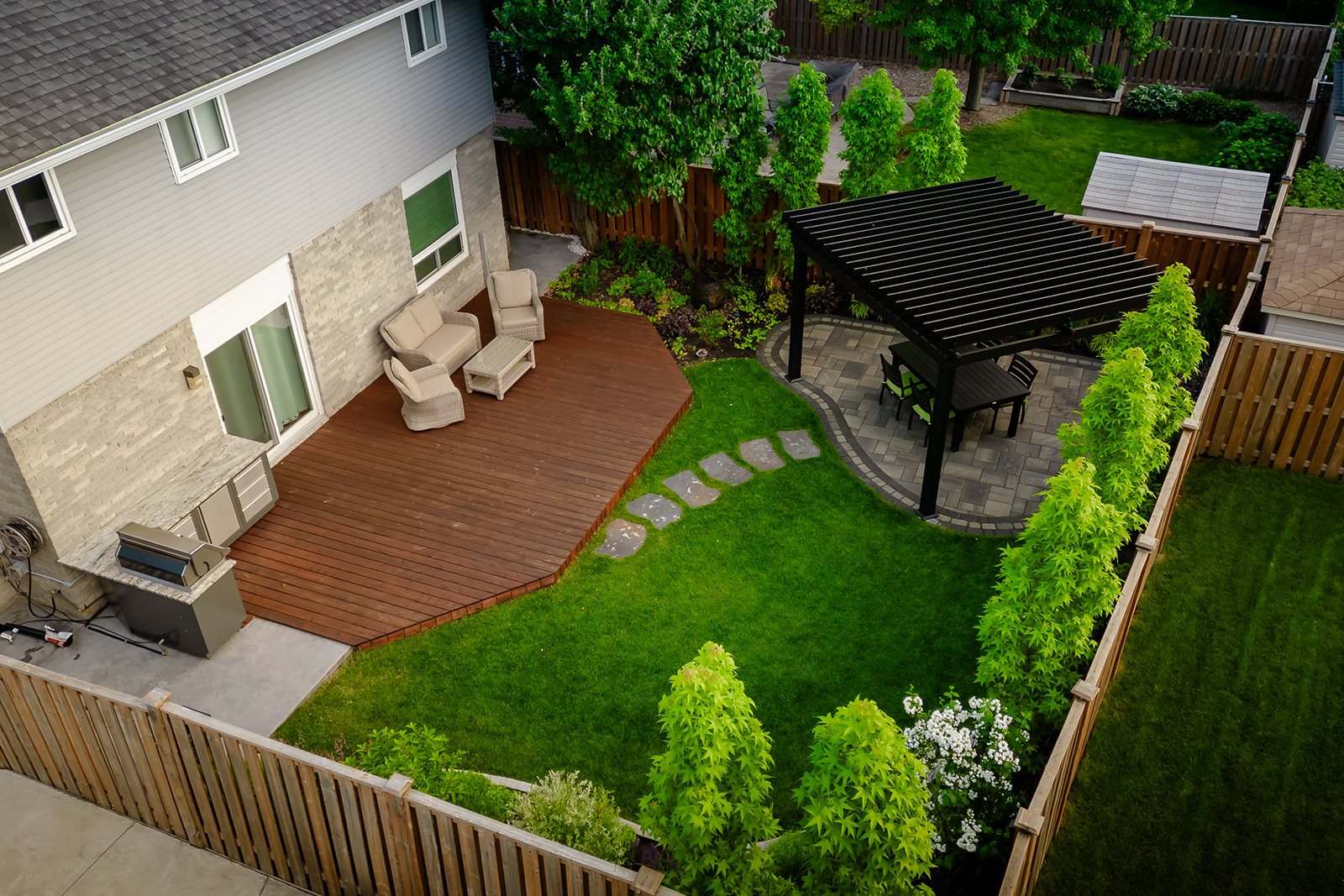 Top-down shot of the backyard with the outdoor seating area on the deck, leading out to the outdoor table.