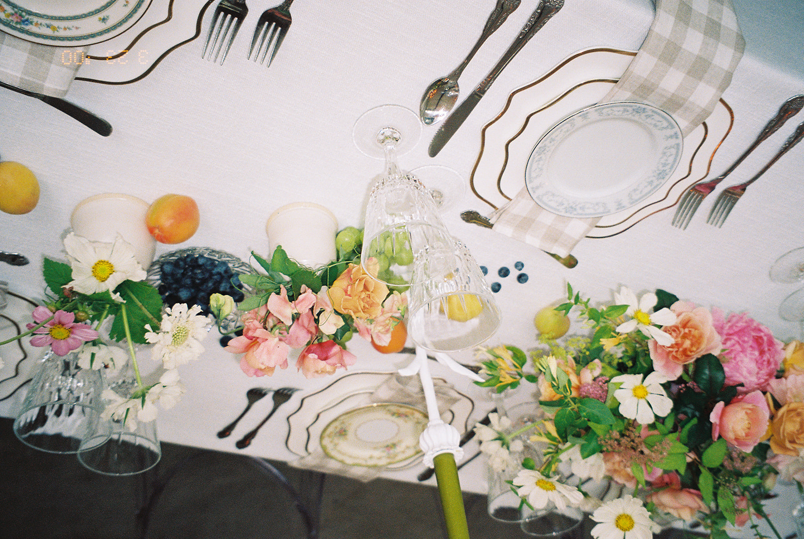 A garden party wedding tablescape captured with film photography featuring bright floral centerpieces and fruit. 