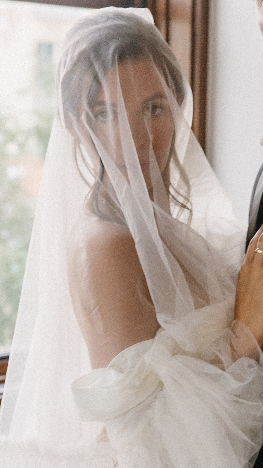 A wedding portrait of a woman through a long, tulle bridal veil. 