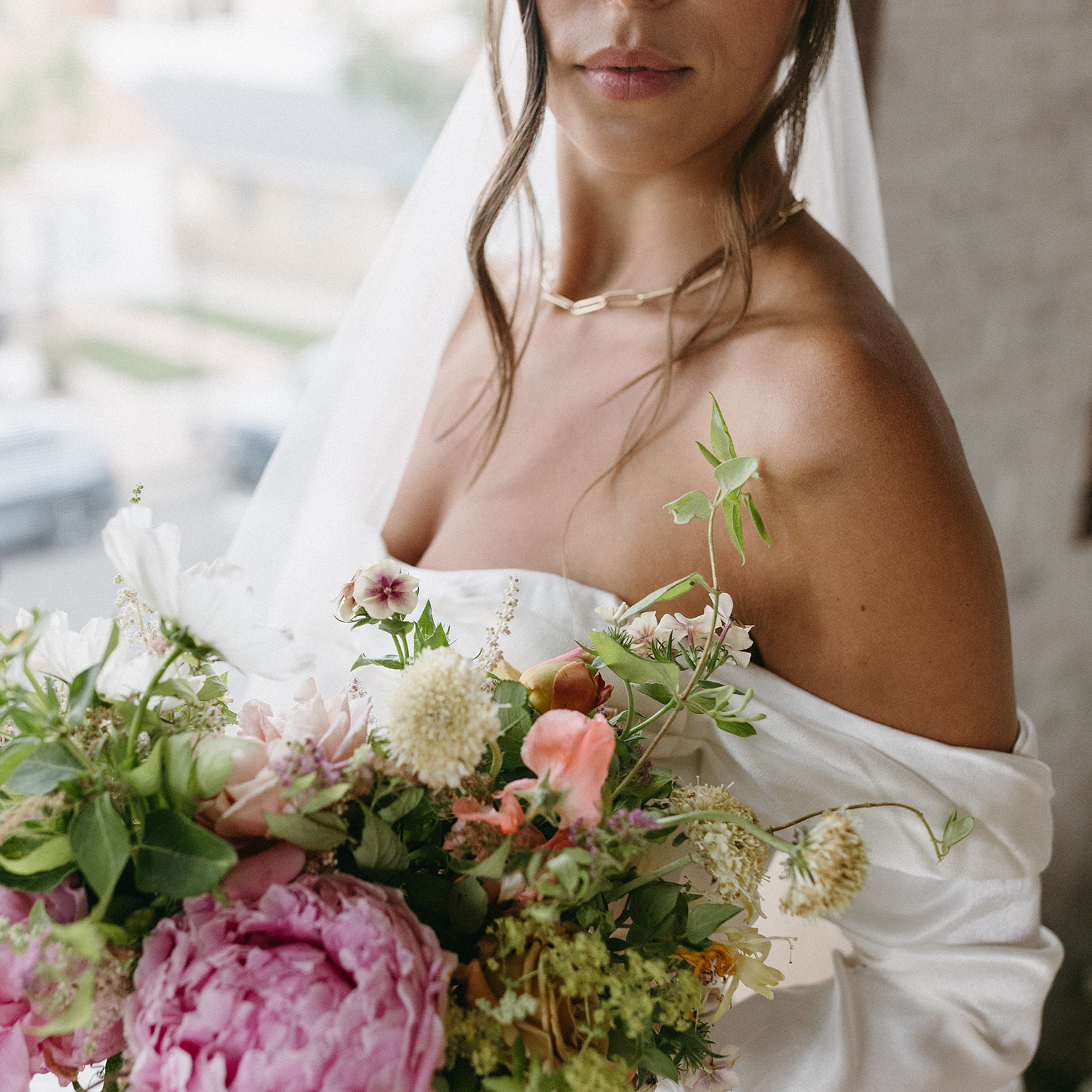 A timeless wedding portrait of a bride in a designer wedding gown holding a bright bridal bouquet made by Figment Floral