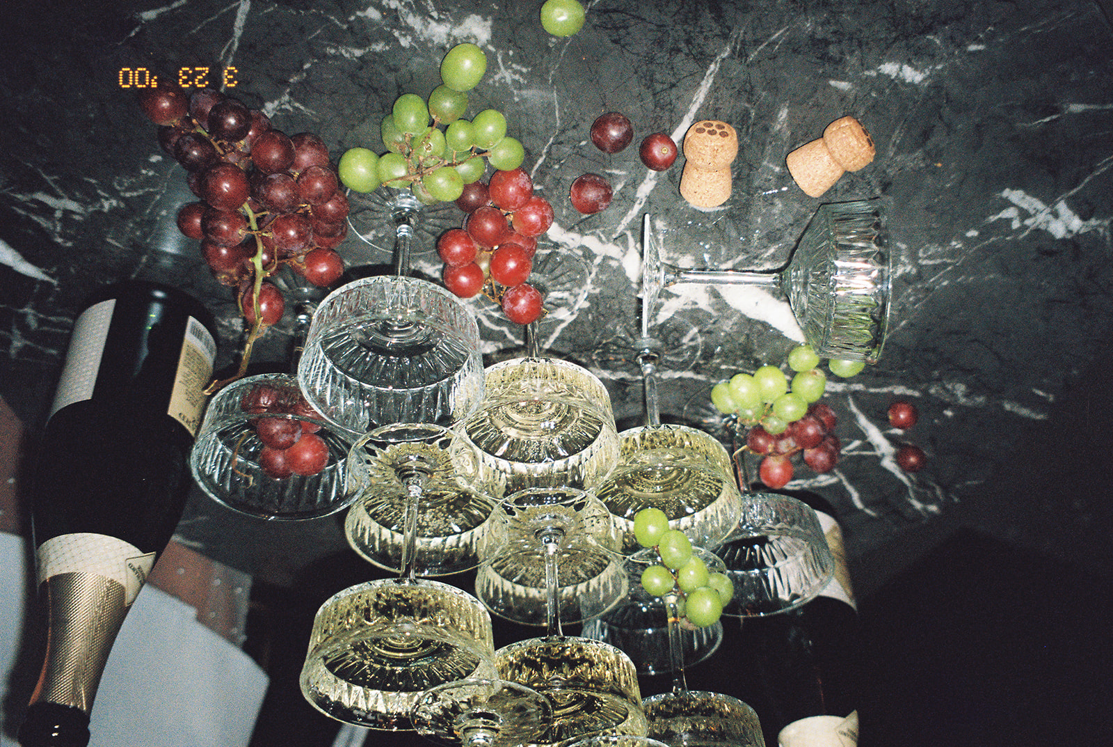 A champagne glass tower on a table decorated with grapes at a speakeasy wedding.