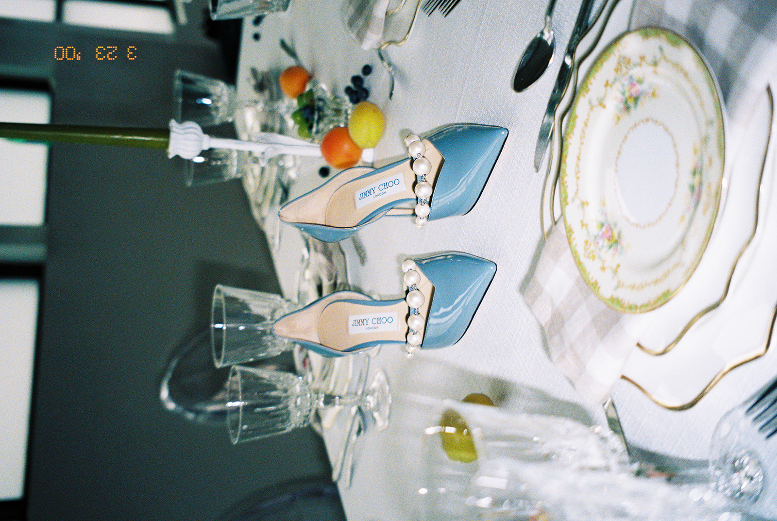 A pair of blue Jimmy Choo wedding heels captured with film photography sitting on a garden party wedding tablescape. 