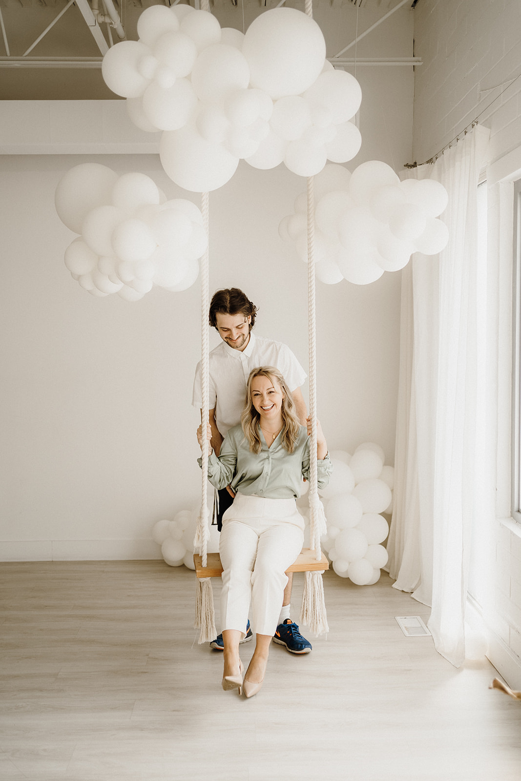 Lady sitting on a swing with a man behind her.