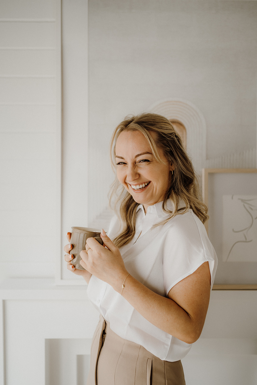 Lady smiling while holding a mug in her hands.