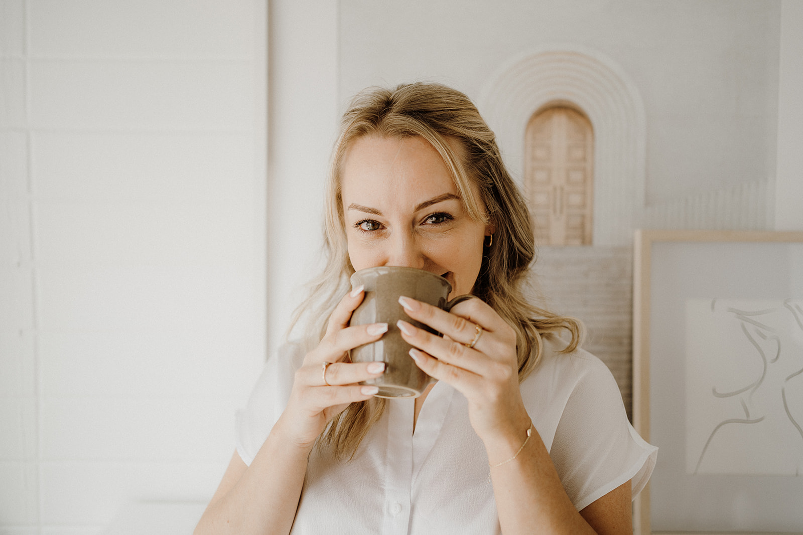 Lady standing holding a mug to her lips with both hands.