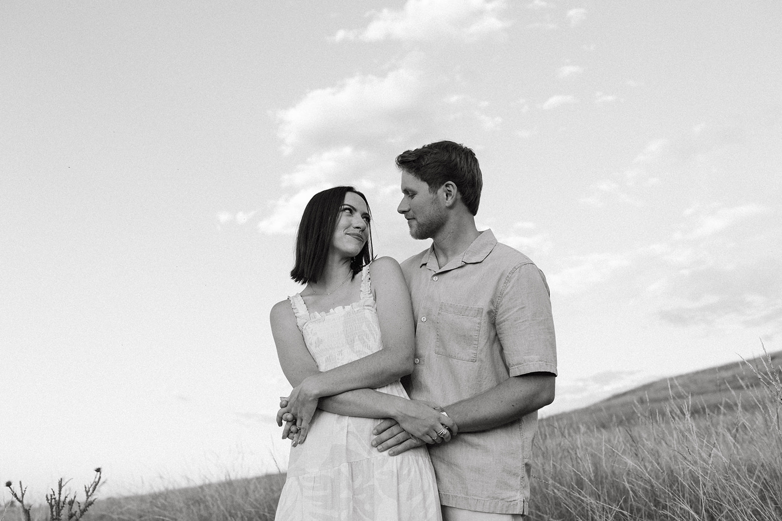 An editorial engagement couple embraces in a wildflower meadow near The Flatirons in Boulder, Colorado