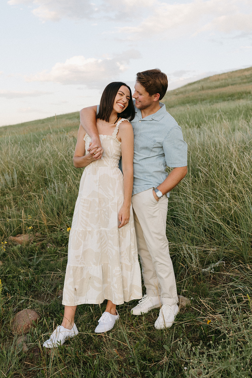 An editorial engagement couple embrace at Sunset in a wildflower meadow near The Flatirons in Boulder, Colorado