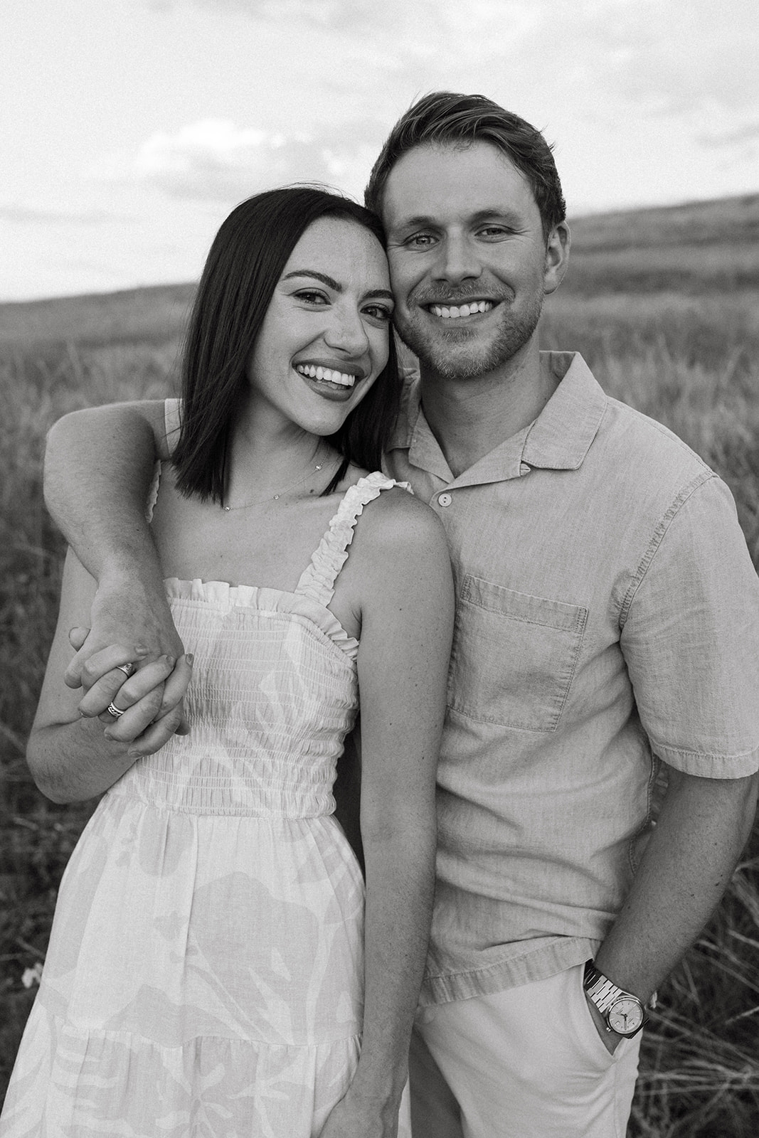 A modern, fashion-forward engagement couple embraces while smiling for a portrait in a wildflower meadow in Colorado