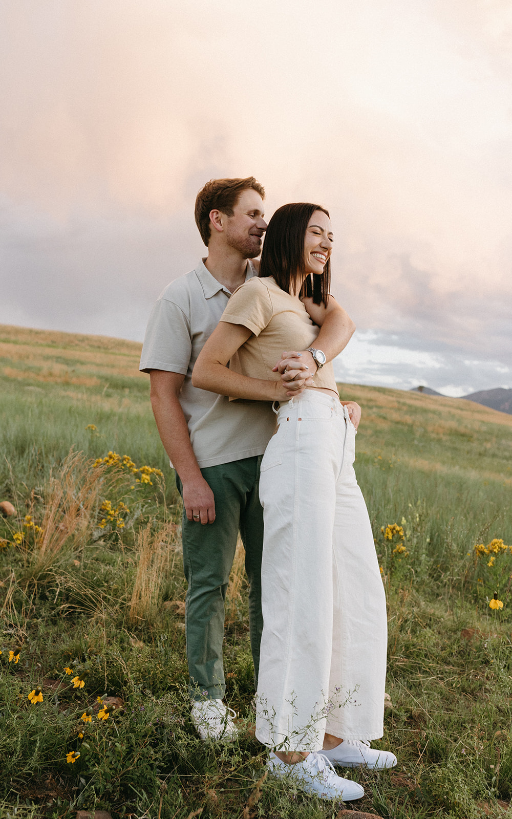 An editorial engagement couple embraces while surrounded by natural scenery in the Colorado Rockies