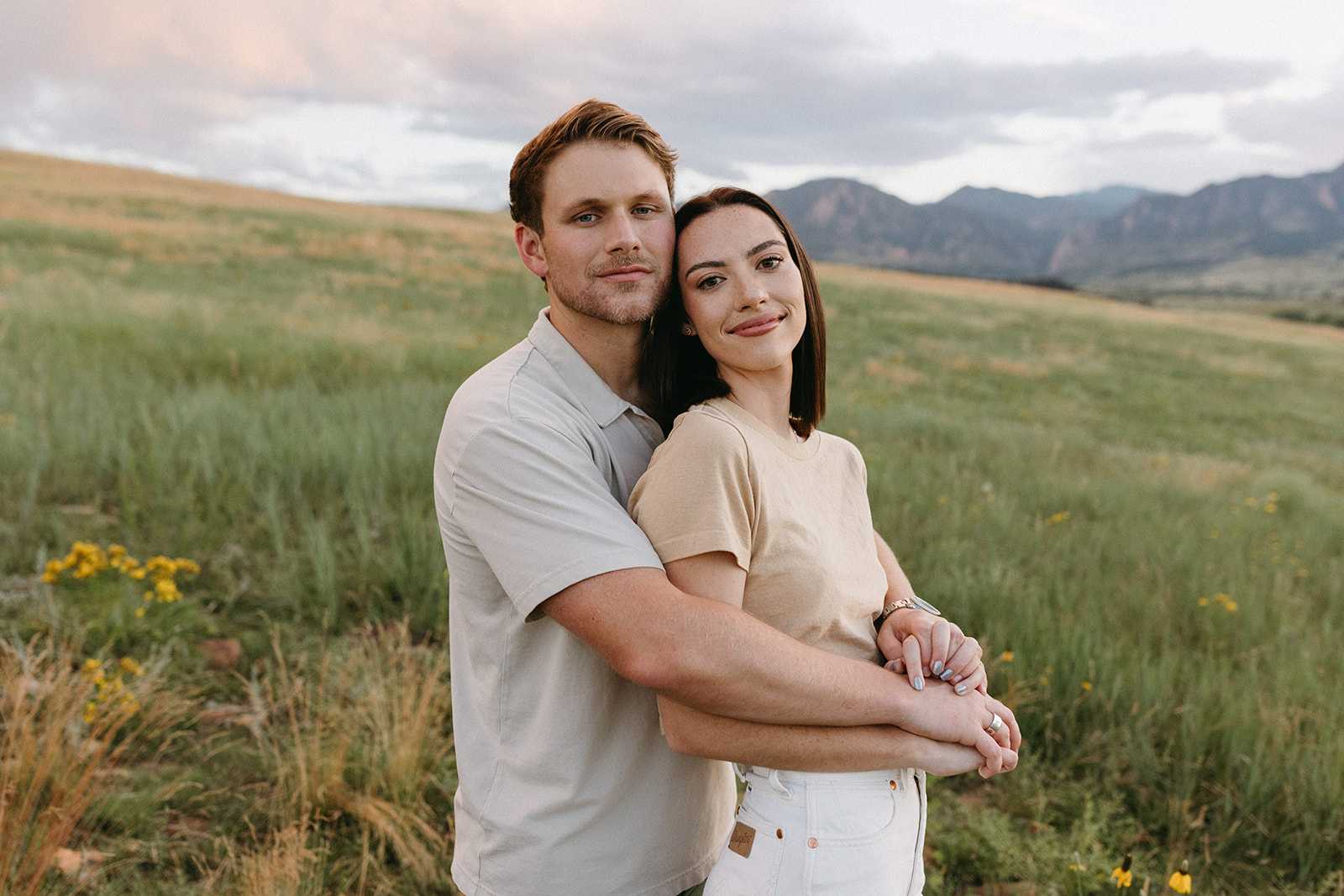 A Colorado engagement session couple embraces while standing in a wildflower meadow at Sunset in Boulder, Colorado