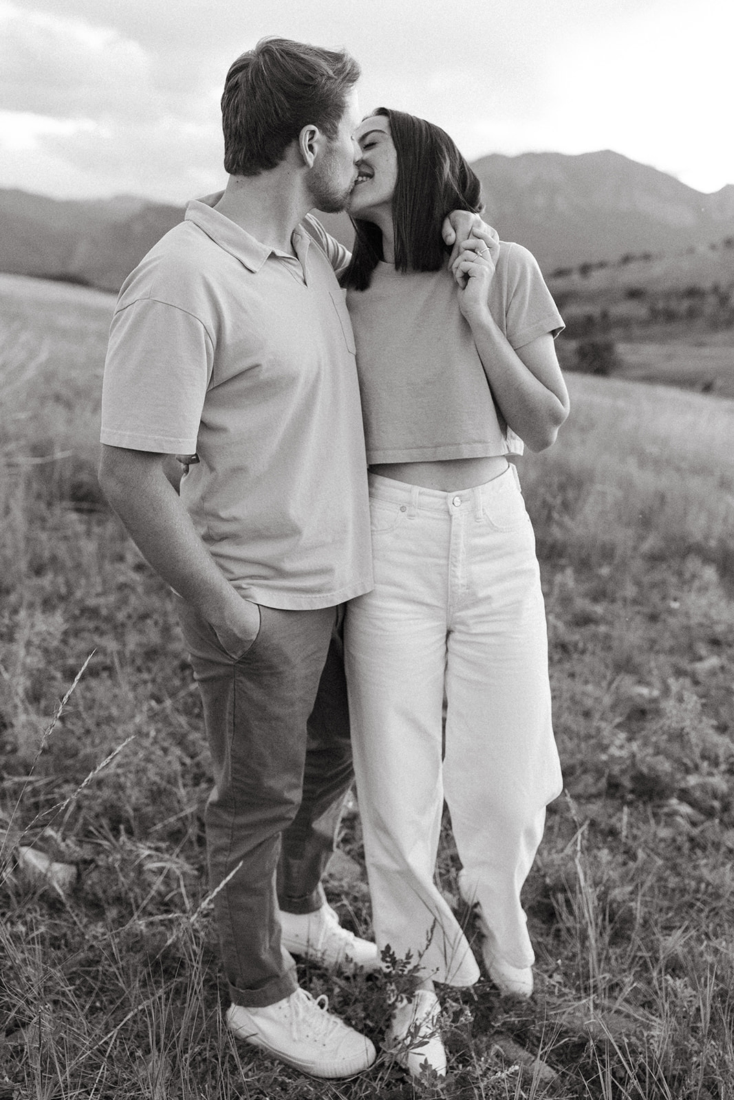 An engaged couple kisses while standing in a wildflower meadow in Boulder for some editorial engagement photos