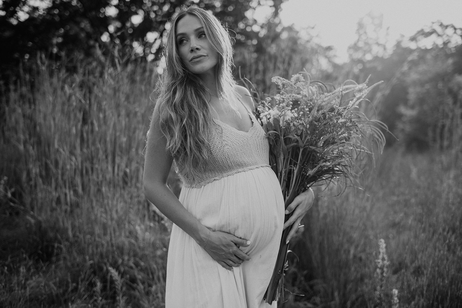 Black and white maternity portrait capturing an expecting mother in a white dress