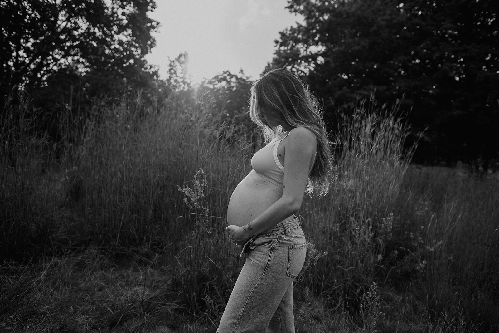 Mom-to-be holds her pregnant belly in a black and white maternity photo