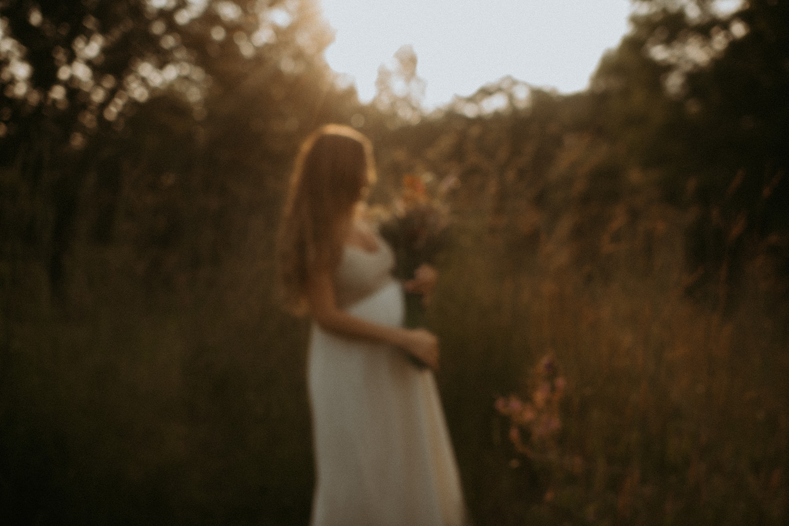 Beautiful sunset maternity portrait of a pregnant woman in a white dress