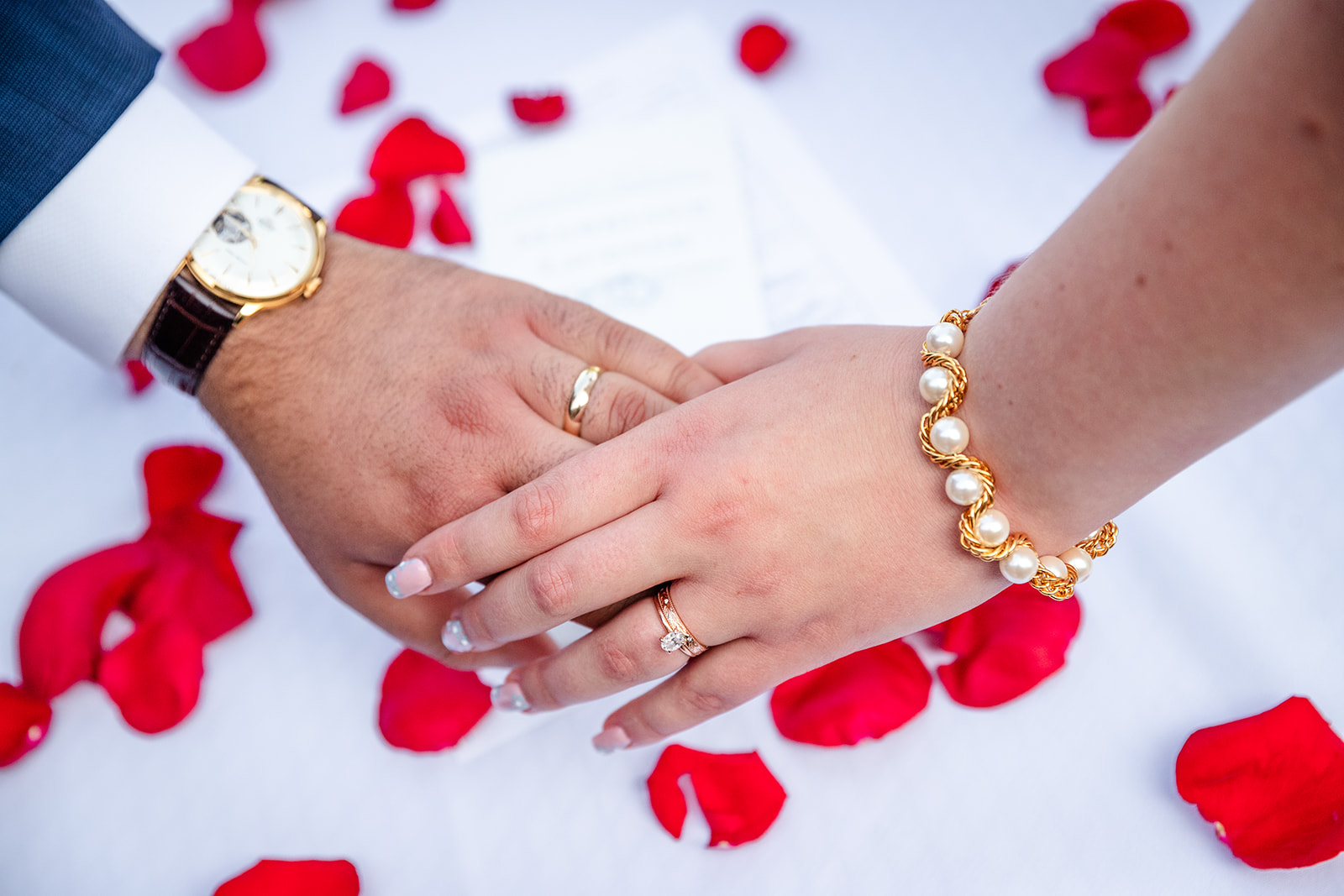 Bride and Groom holding hands with rose pedals in background
