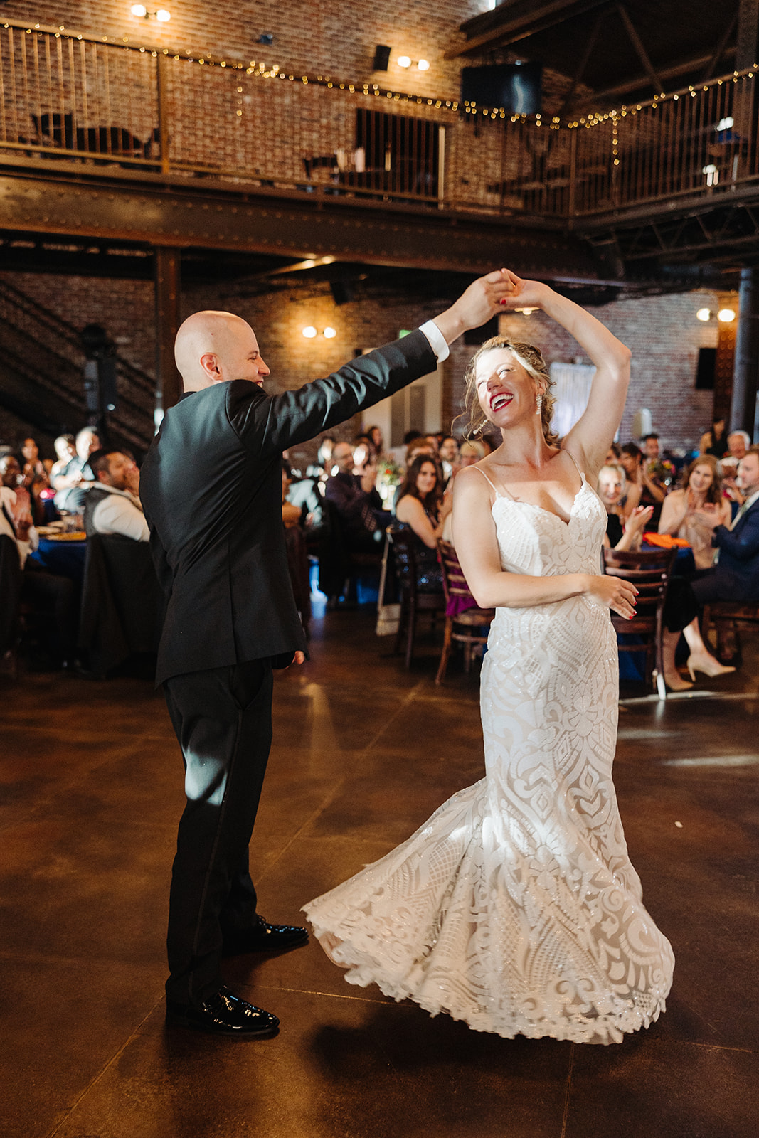 The groom twirls his new wife during their first dance at their industrial Mile High Station wedding.