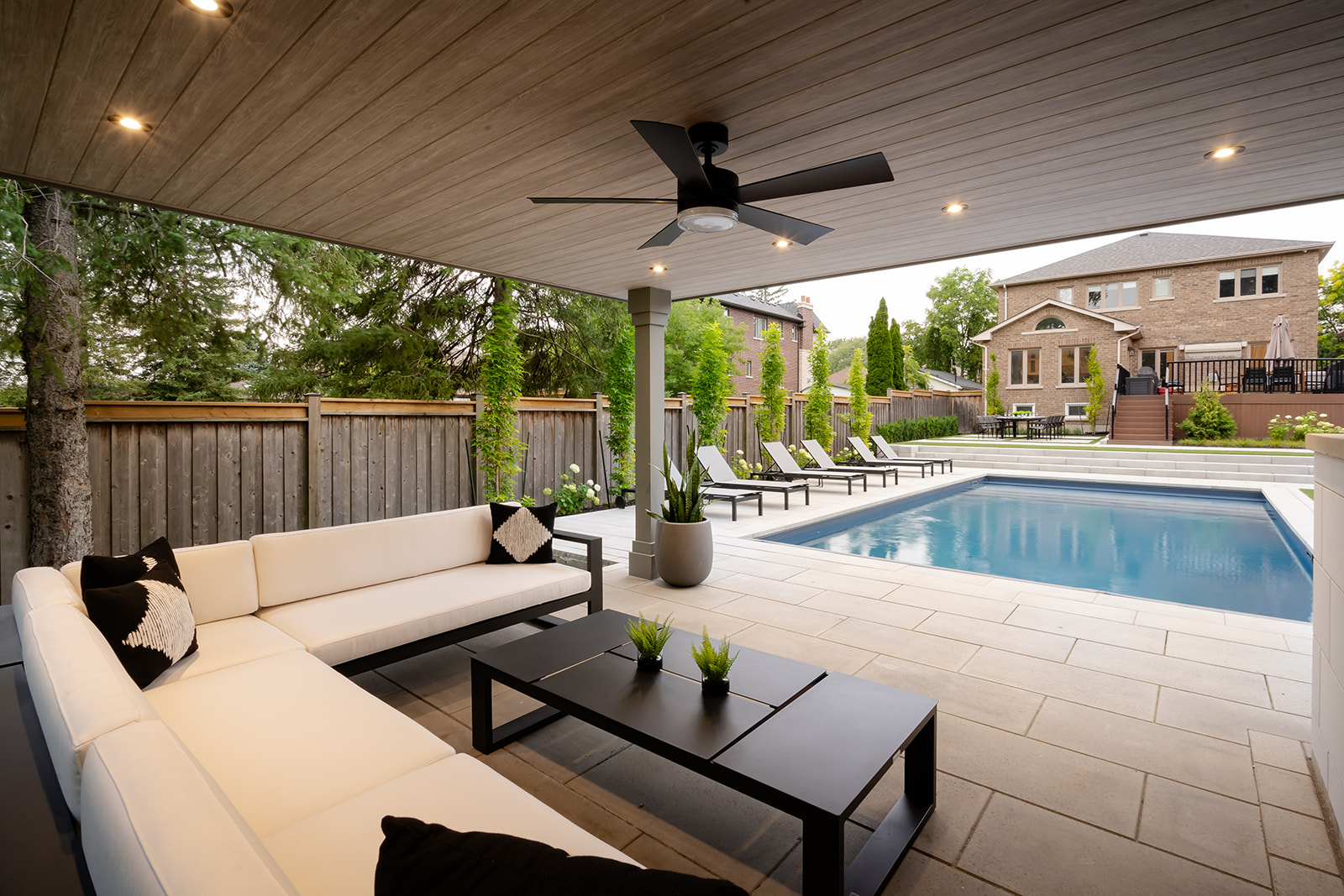 A seating area underneath an awning and a pool on the right.
