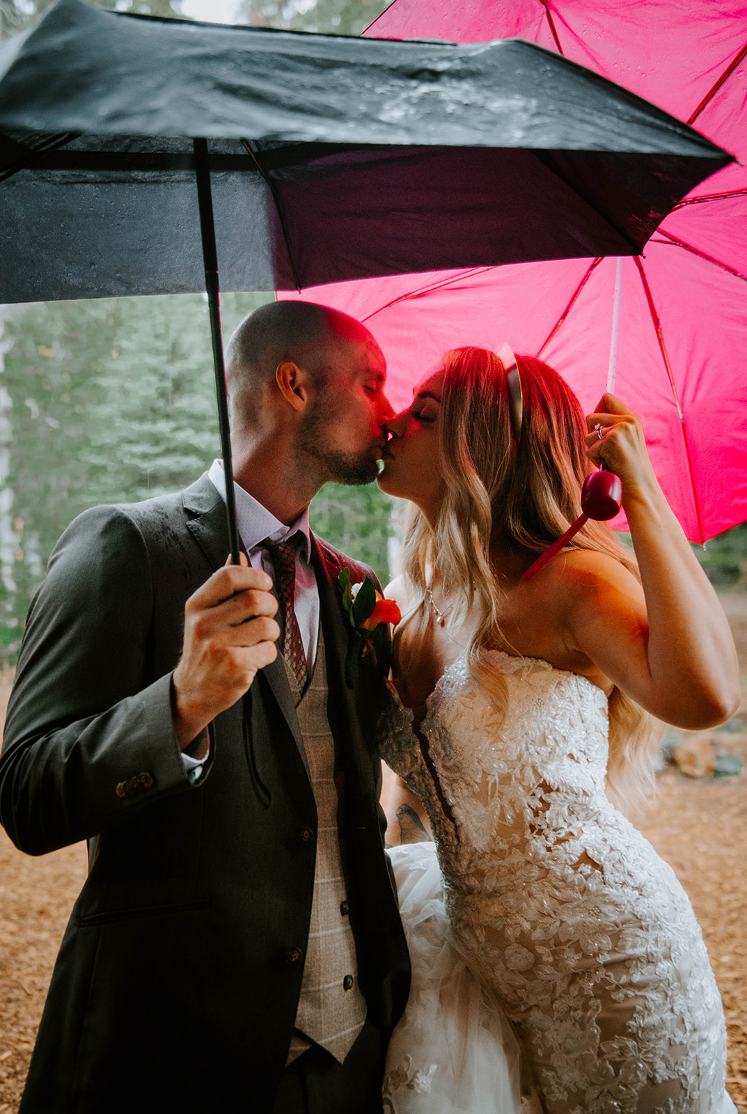 Bride and groom kissing under black and pink umbrella's