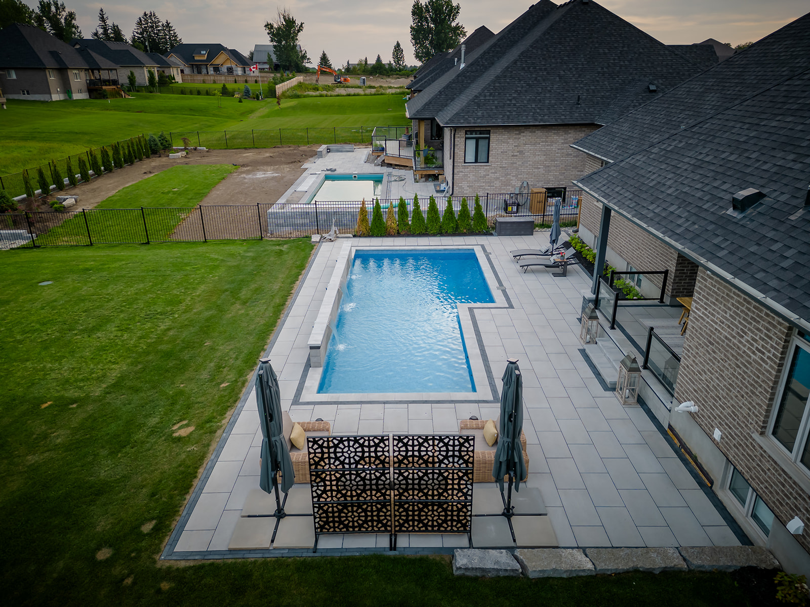 An inground pool with seating area toward the front, stairs going into the house on the right and lounge chairs.