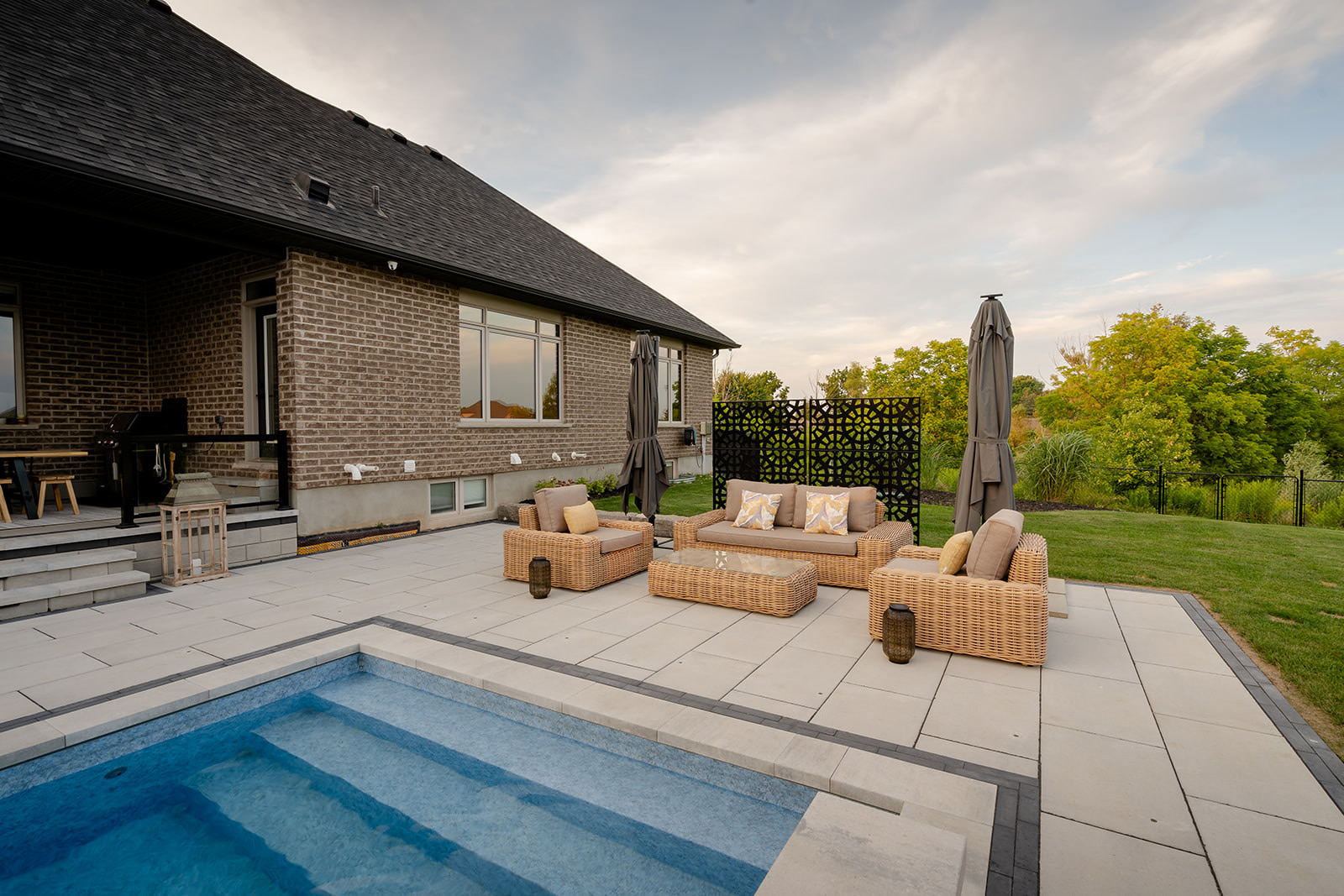 An outdoor seating area with and an inground pool in front.