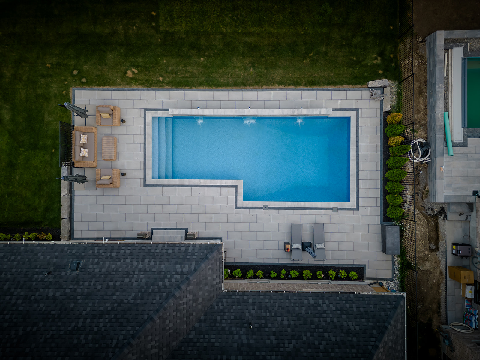 Top-down view of an inground pool, seating area to the left and two lounge chairs to the right.